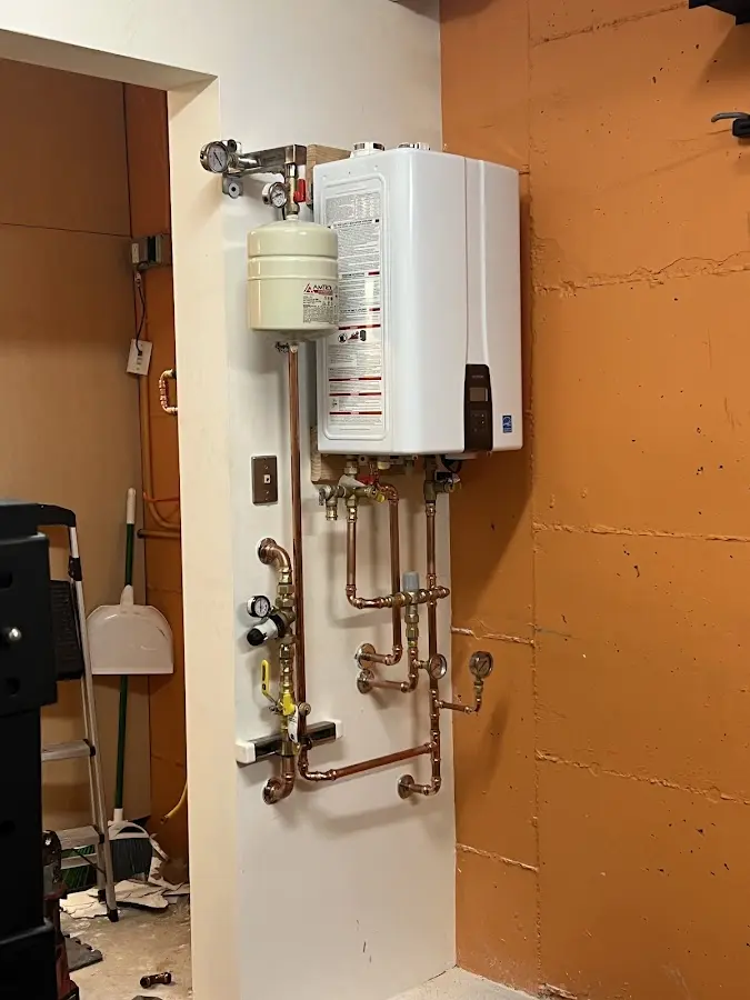 Plumbing technician inspecting water heater connections in Boxborough